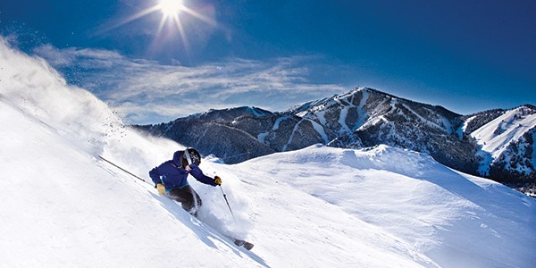 A person kis powder down Dollar Mountain with Bald Mountain in the background.